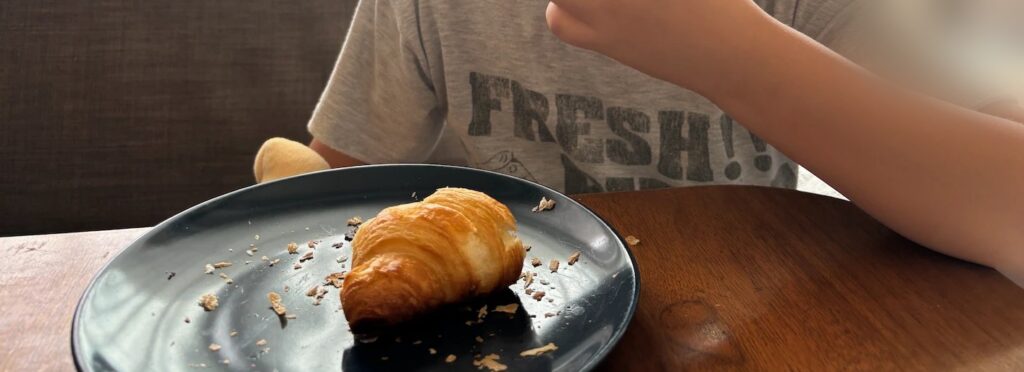 スタイルブレッド（STYLE BREAD）のはじめてパンセットに入っている至福のクロワッサンをお皿にのせて食べているところ。パイのかけらがお皿に散らばるほどサクサク
