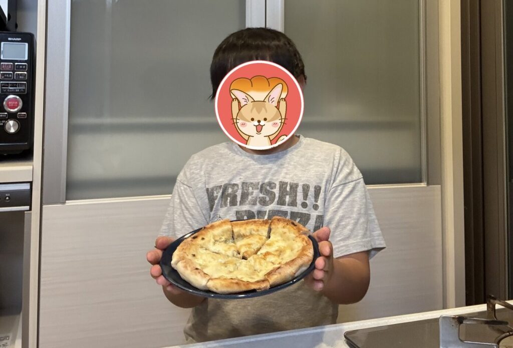 スタイルブレッド（STYLE BREAD）のピザ「クワトロフォルマッジ」を持つ子ども（顔は隠しています）